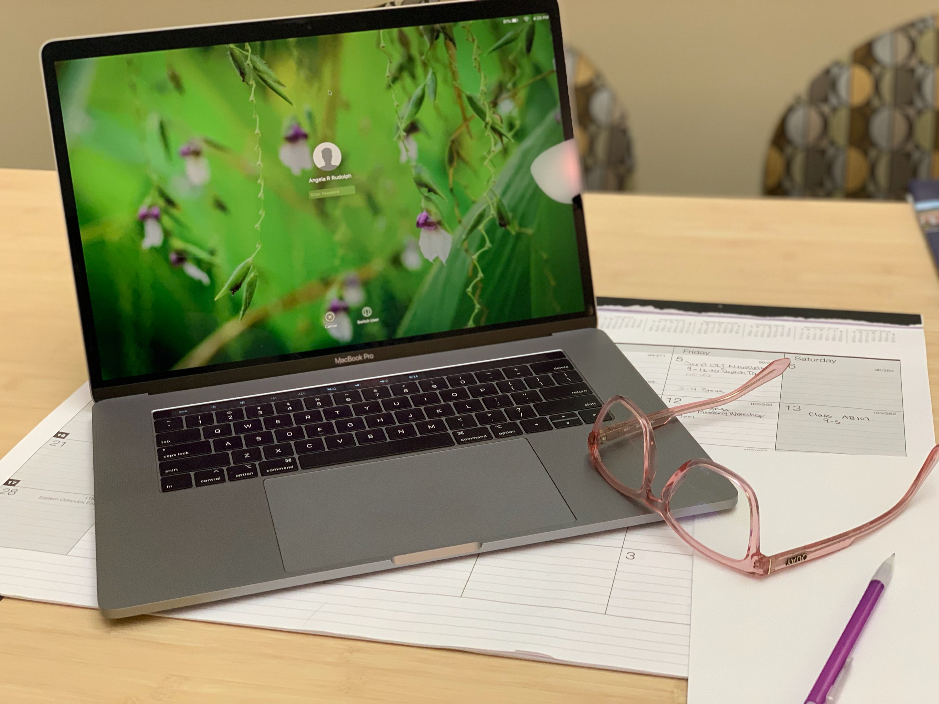 Computer on desk with glasses and paper nearby