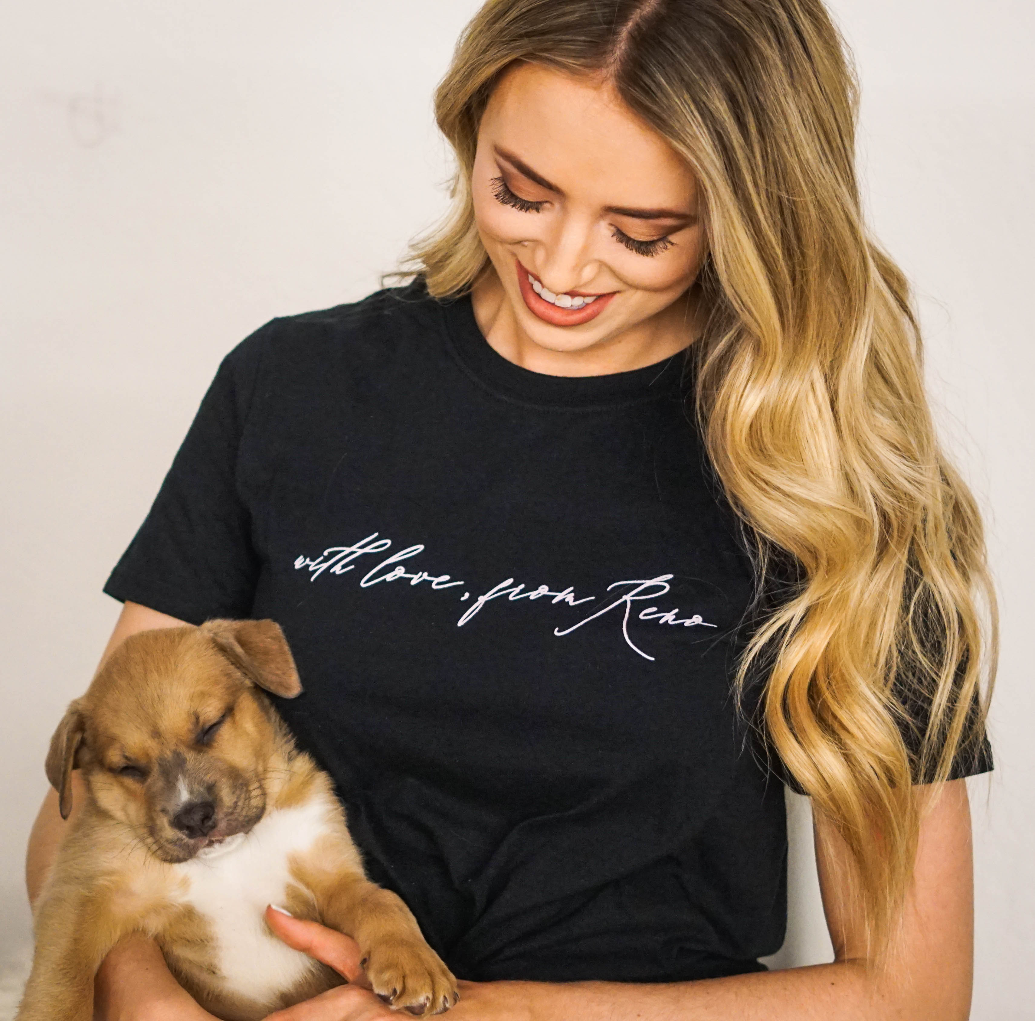 Woman in a t-shirt from a local clothing store holding a sleeping puppy from the SPCA.