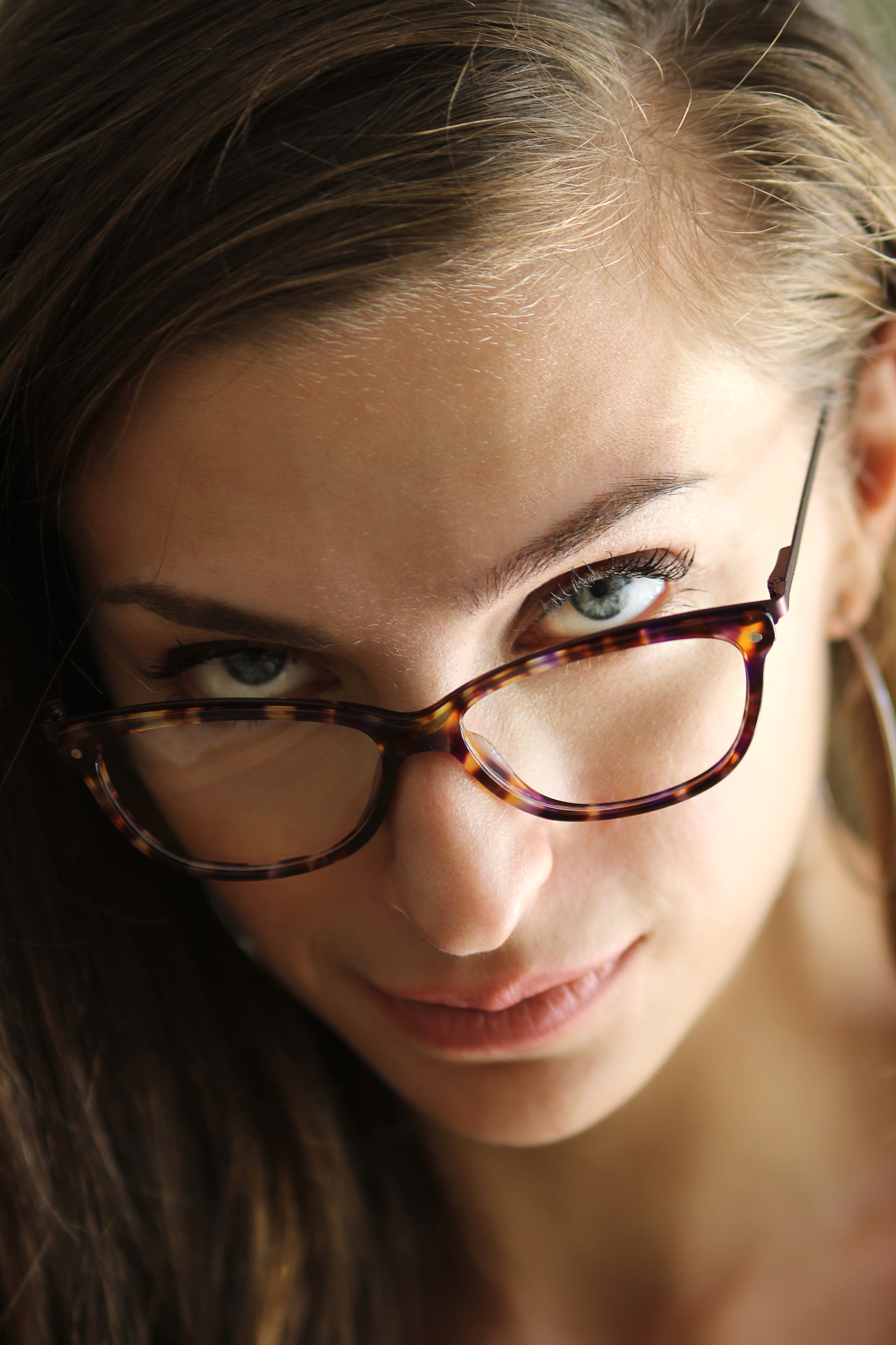 Skeptical woman looking at the camera with her glasses pushed down her nose. 