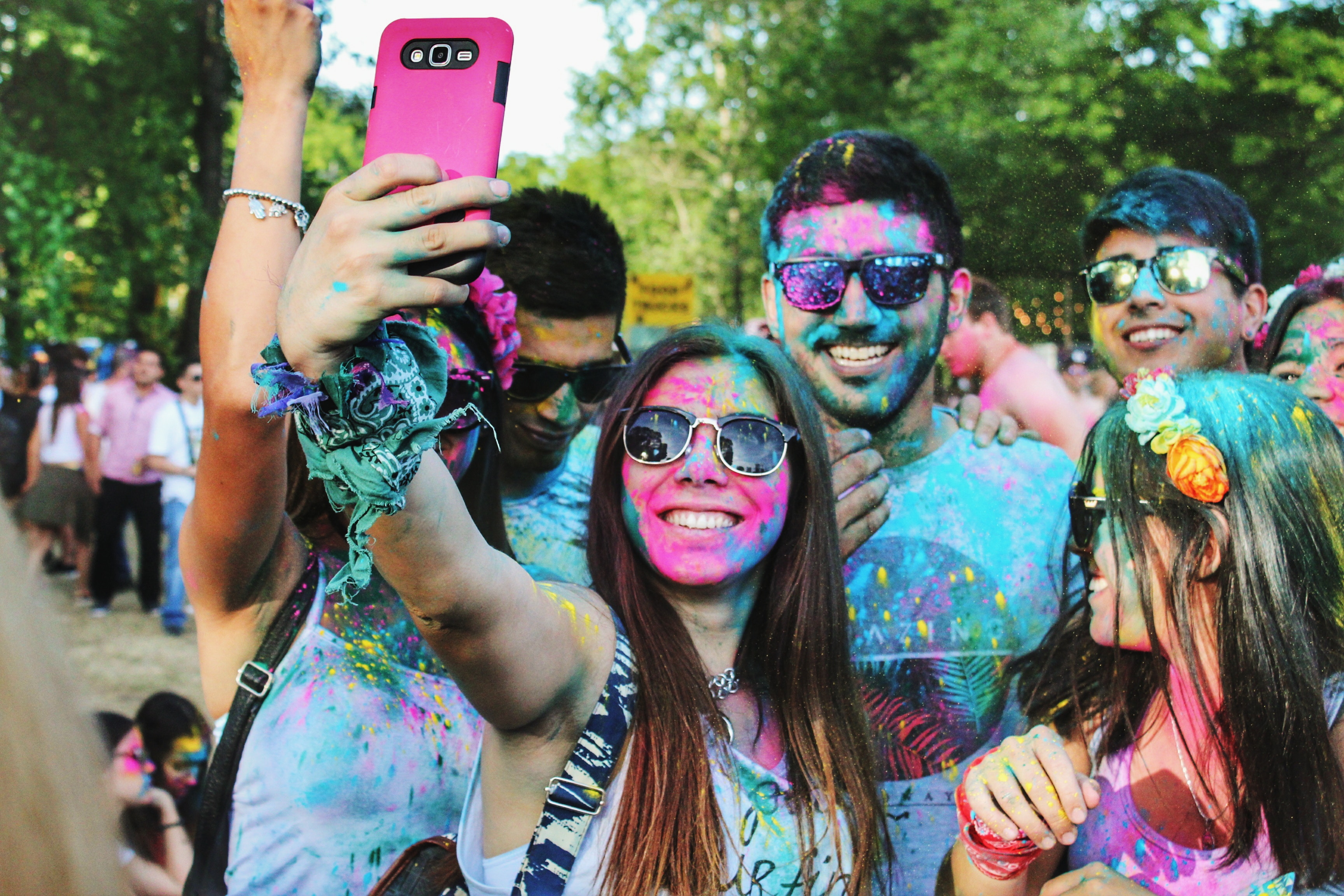 Group covered in paint smiling and taking a picture on a cell phone.